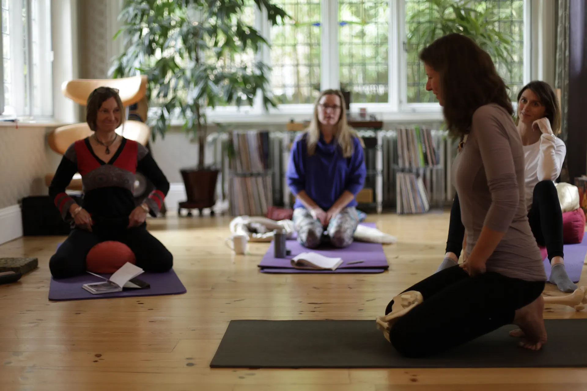 yoga students gathered around a yoga teacher in a yoga workshop