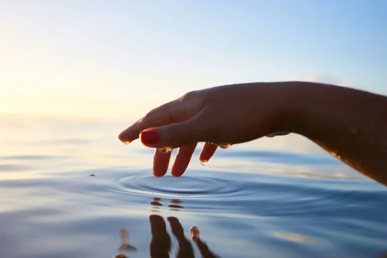 a hand about to touch water for somatic yoga