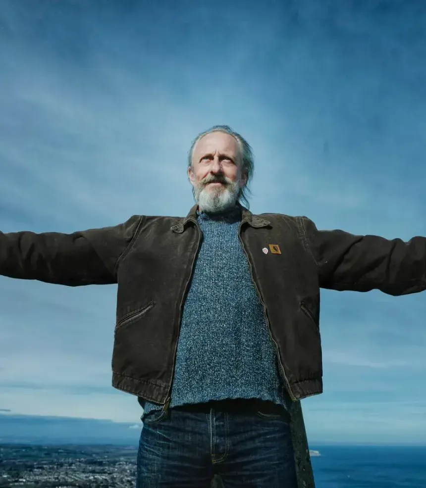Erling McCracken with his arms outstretched against a blue sky above the Isle of Wight